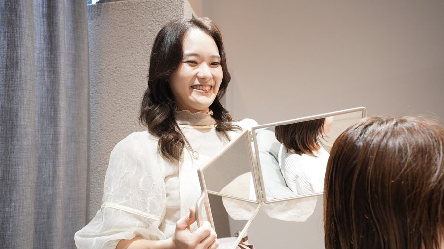 お客様に鏡を見せる笑顔のスタイリスト
